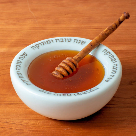 Handcrafted ceramic honeypot with a wooden honey dipper, featuring a smooth, minimalist design. Perfect for serving honey during Jewish holidays and special occasions. Available at Green Judaica.