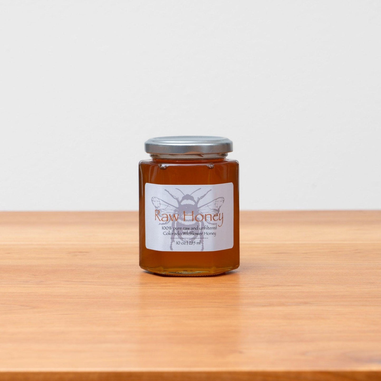 Jar of raw Colorado wildflower honey, beautifully golden and pure, showcasing its natural richness. Handcrafted in 10oz jars, perfect for Rosh Hashanah or everyday enjoyment. Available at Green Judaica.